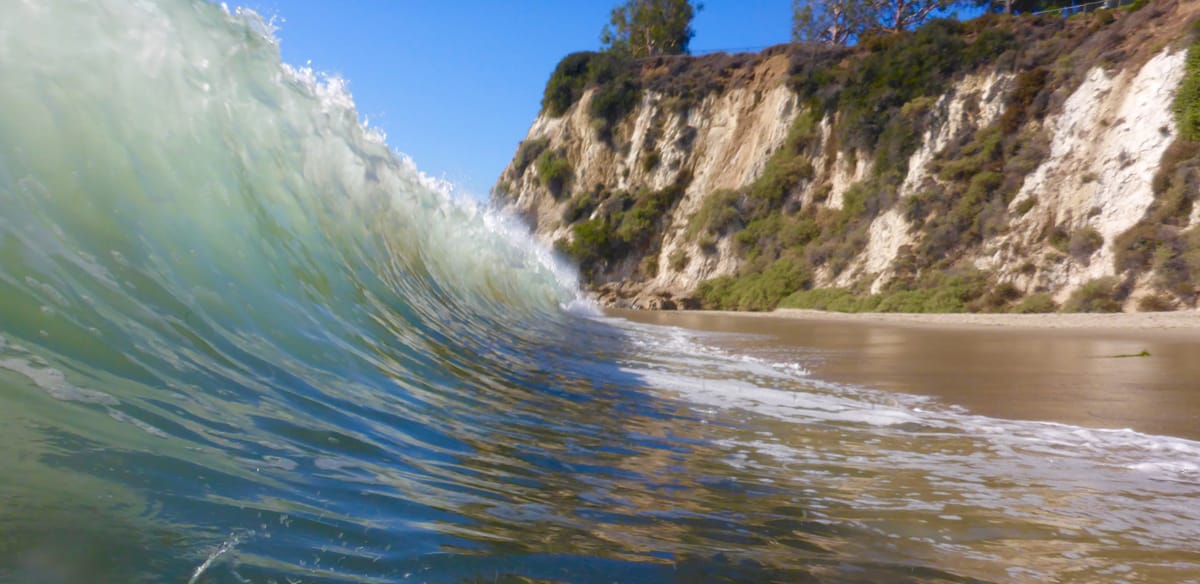 Picture of a breaking wave in front of a rocky beach